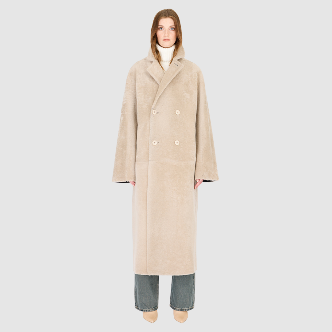 The DANIELLE Duster is a statement in heritage-inspired luxury and modern versatility. Crafted in black beige nappa and plush iron wool shearling, this reversible oversized coat transitions effortlessly from sleek leather to cozy teddy texture. Its elongated silhouette is enhanced with a slight drop shoulder, back vent, and double-breasted button closure, creating timeless elegance with functional edge. Practical single welt pockets on the suede side and slash pockets on the wool side