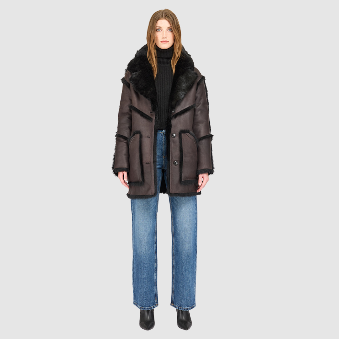 The LUREEN Coat is a luxury reversible semi-suede outerwear piece crafted in Java Toscana. Designed to flip seamlessly from smooth semi-suede to plush Toscana wool teddy, it offers versatile styling for cold-weather layering. The wool-out Toscana seam detailing on the semi-suede side, combined with a drop shoulder and relaxed fit through shoulders, arms, and torso, creates effortless volume and structure. An oversized Toscana notch collar, patch pockets on both sides, and a front button closure.