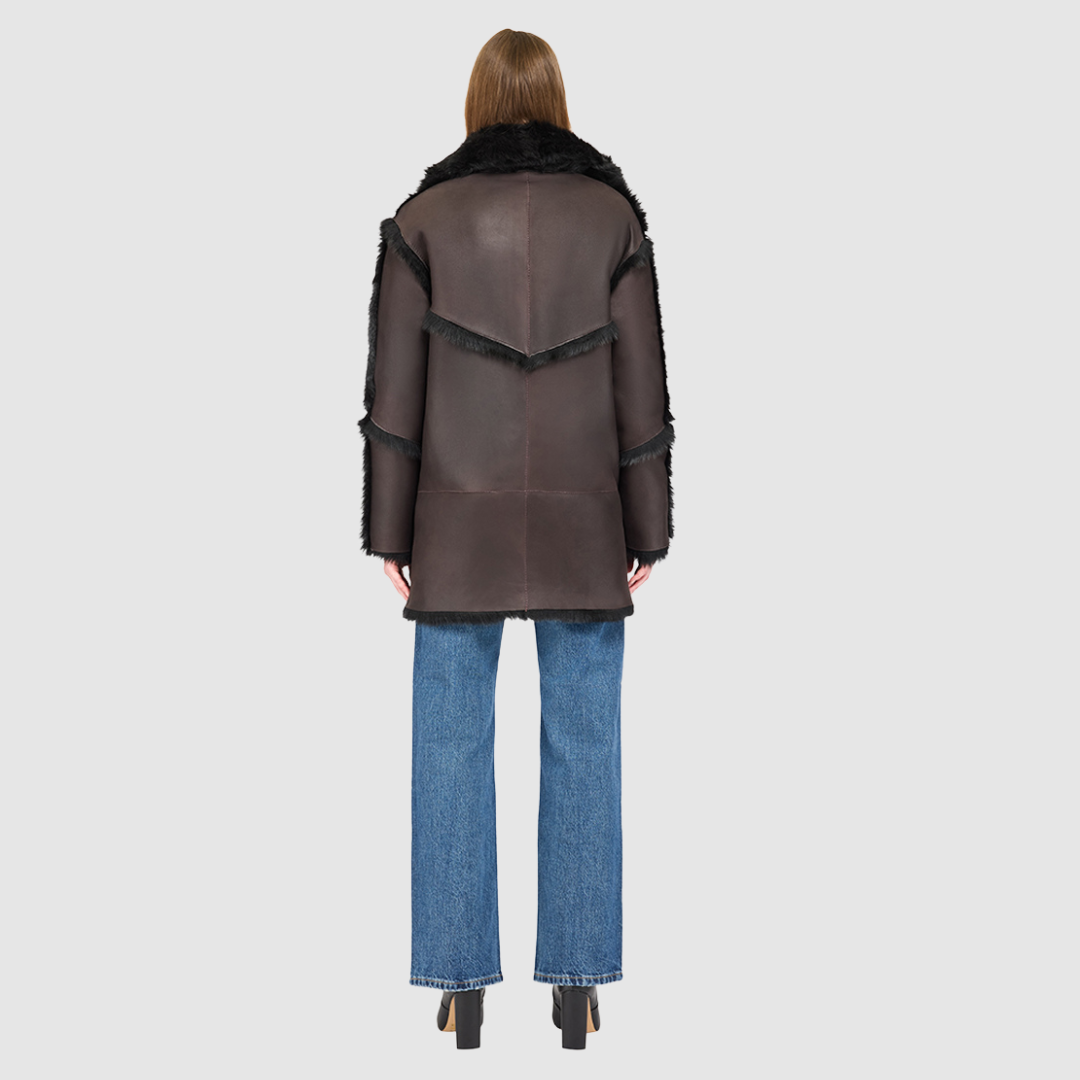 The LUREEN Coat is a luxury reversible semi-suede outerwear piece crafted in Java Toscana. Designed to flip seamlessly from smooth semi-suede to plush Toscana wool teddy, it offers versatile styling for cold-weather layering. The wool-out Toscana seam detailing on the semi-suede side, combined with a drop shoulder and relaxed fit through shoulders, arms, and torso, creates effortless volume and structure. An oversized Toscana notch collar, patch pockets on both sides, and a front button closure.