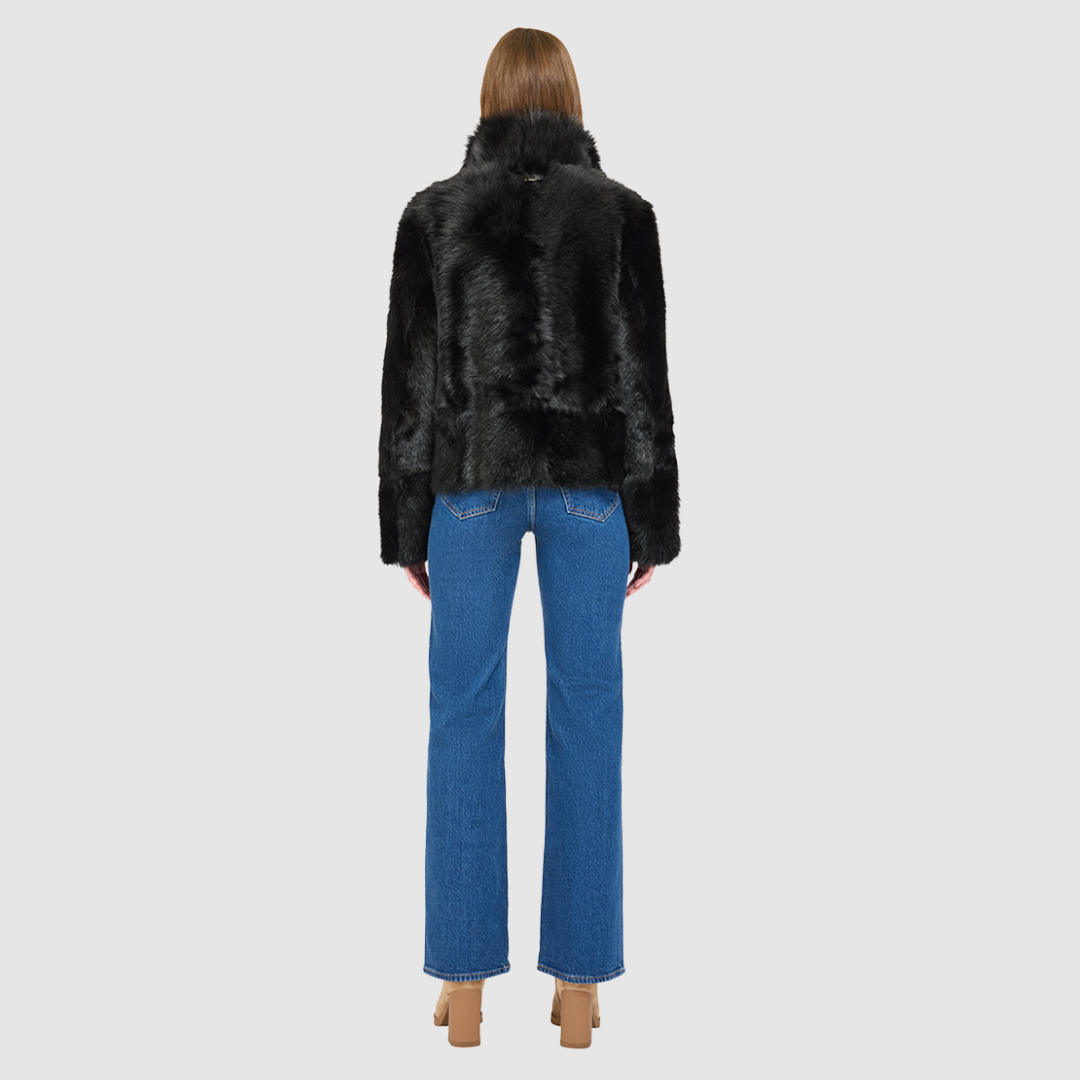 This cropped teddy jacket features a reversible design, with wool-out on one side and nappa-out on the other. The relaxed shoulder, spread collar, and slash side pockets provide comfort and functionality, while the front zip closure adds a practical touch.