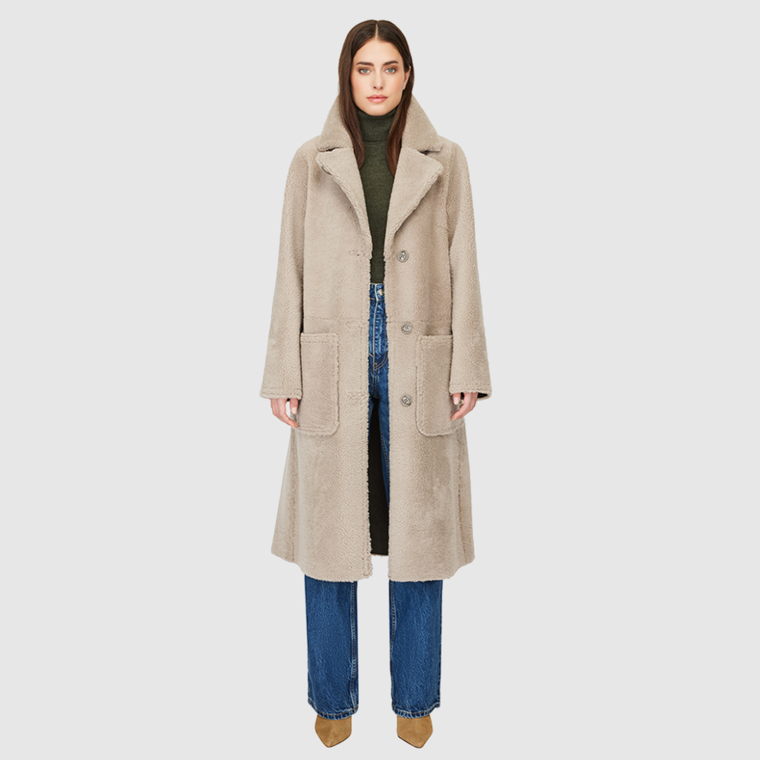Introducing Zira, our vintage-inspired reversible nappa curly wool shearling coat. This elegant piece features a classic notch collar and effortlessly reverses to a cozy curly wool teddy. Designed with a relaxed dropped shoulder, 3-button closure, and a tie belt at the waist for a flattering fit, it offers both style and comfort. Practical zip pockets on the nappa side reverse to patch pockets on the teddy side, making Zira a versatile must-have for winter fashion.