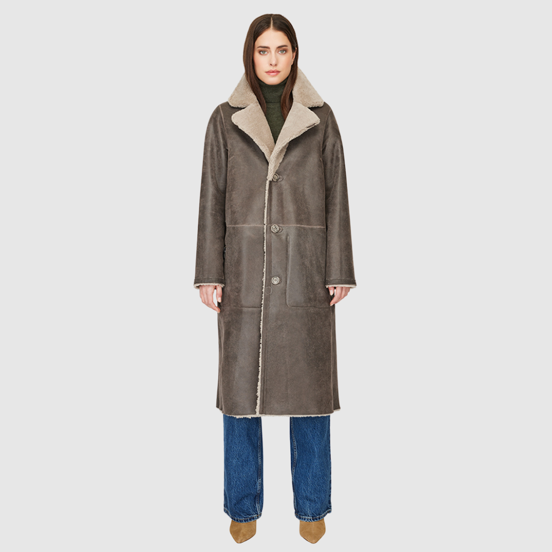 Introducing Zira, our vintage-inspired reversible nappa curly wool shearling coat. This elegant piece features a classic notch collar and effortlessly reverses to a cozy curly wool teddy. Designed with a relaxed dropped shoulder, 3-button closure, and a tie belt at the waist for a flattering fit, it offers both style and comfort. Practical zip pockets on the nappa side reverse to patch pockets on the teddy side, making Zira a versatile must-have for winter fashion.