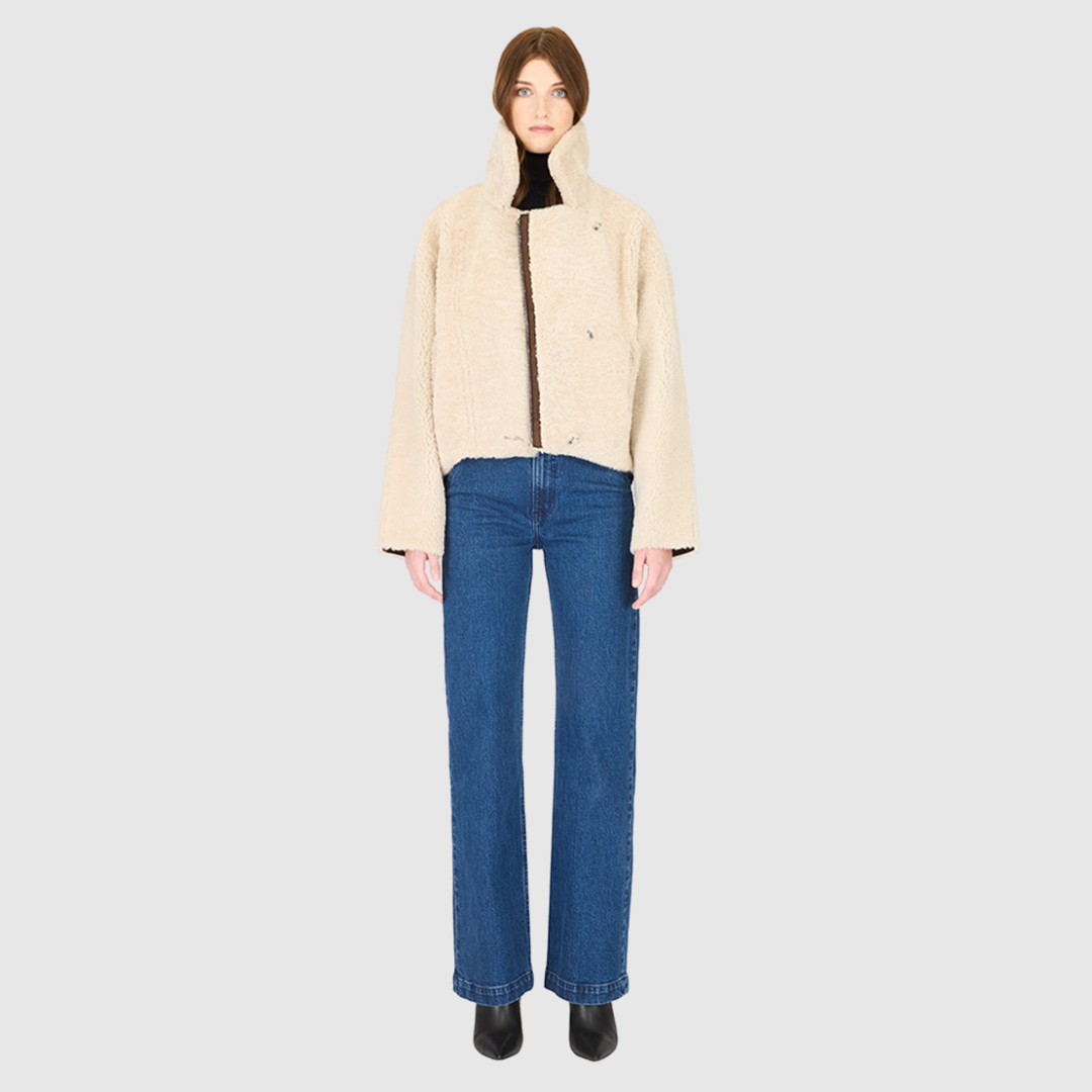 Introducing our women's reversible nappa cropped moto**, perfect for winter. This relaxed-fit coat reverses to a cozy curly wool teddy and features a drop shoulder and relaxed batwing sleeves for a chic look. The oversized notch collar adds bold style, while single welt side pockets on the nappa side and slash pockets on the curly wool side offer practicality. Finished with an asymmetrical front zip and single button closure, it's a versatile wardrobe essential.