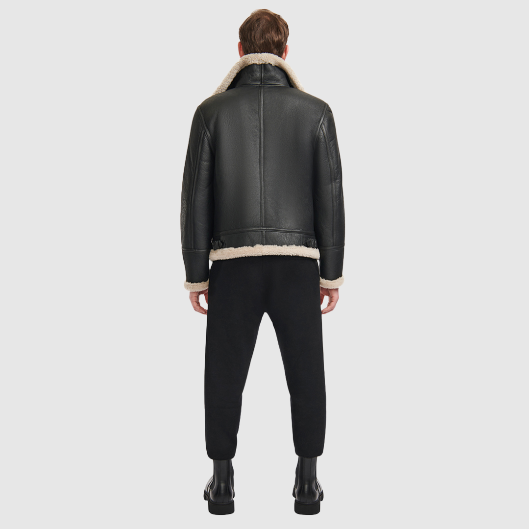 The Ariel Black Beige Shearling Aviator Jacket channels classic aviator style with a modern update, crafted from supple nappa leather and lined with curly wool shearling. Featuring a curly wool collar and trims, oversized welt pockets with stitch detailing, and adjustable buckle details at the collar and waistband, it combines utility with timeless edge. A standard zip closure ensures functionality, while the structured silhouette offers a confident, versatile fit.