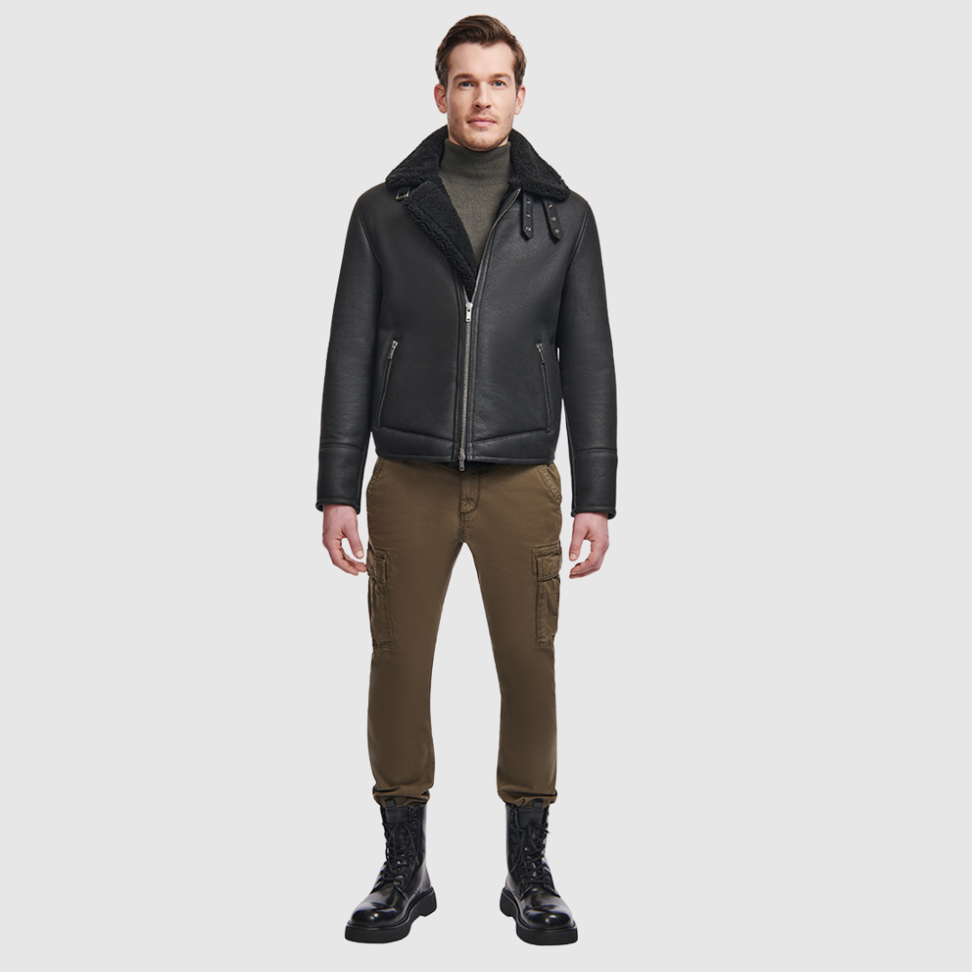 The Code Black Shearling Moto is a bold reinterpretation of a classic moto jacket, merging sleek nappa leather with plush curly wool shearling. Designed for a true-to-size fit, it features a spread collar with a buckle detail for added edge, a standard front zip closure, and an interior zip pocket for functionality. This piece balances rugged refinement with modern versatility, making it a cold-weather essential.