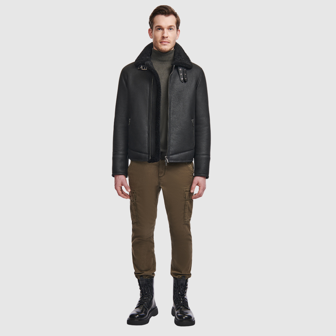 The Code Black Shearling Moto is a bold reinterpretation of a classic moto jacket, merging sleek nappa leather with plush curly wool shearling. Designed for a true-to-size fit, it features a spread collar with a buckle detail for added edge, a standard front zip closure, and an interior zip pocket for functionality. This piece balances rugged refinement with modern versatility, making it a cold-weather essential.
