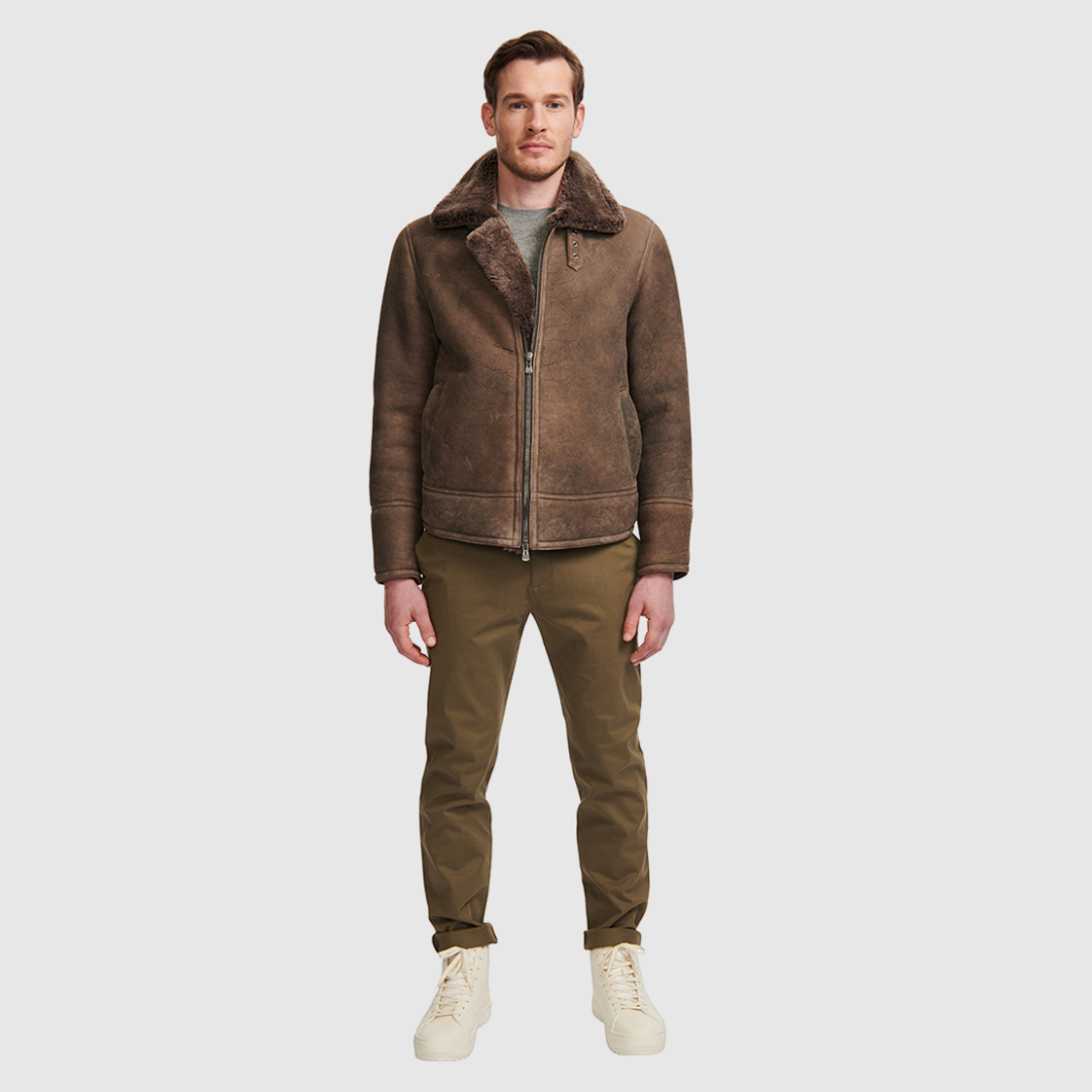 The Kane Brown Ancient Shearling Moto combines heritage craftsmanship with modern moto design. Crafted from supple nappa leather with a plush curly wool collar, it fits comfortably through the shoulders and chest for ease of movement. Featuring a notch collar with buckle detailing, interior patch pockets, and exterior single welt side pockets, it balances functional utility with polished style. A front zip closure completes the sleek, timeless silhouette.