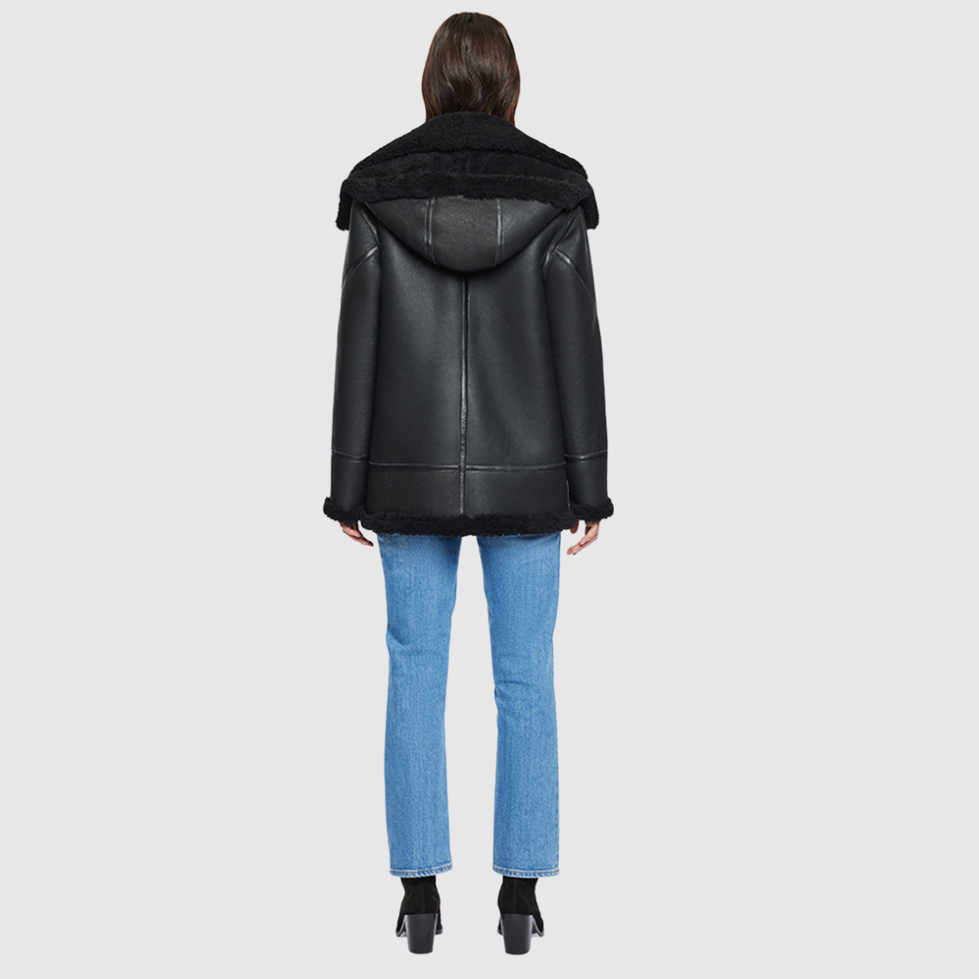 The HiSO Martina Jet Shearling is crafted with a Nappa material and features a relaxed medium length. Along with a curly wool collar and trims, it includes a drop shoulder design and a detachable hood for added convenience. The asymmetrical front zip closure and exterior zip pockets add a sleek touch, while hidden inside pockets provide added functionality.