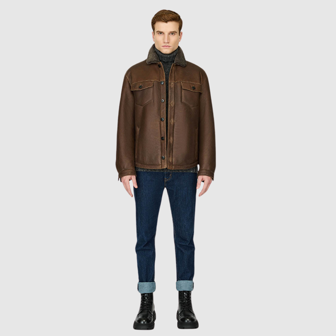 The PARRY Aged Bourbon Shearling Jacket delivers rugged refinement with a modern utilitarian edge. Crafted from semi-suede shearling, it features a semi-curly wool stand collar and a clean, semi-fitted silhouette through the shoulders, arms, and torso. Functional detailing includes chest patch pockets, sleeve button cuffs, and a mix of interior and exterior pockets for versatility. Finished with a single-breasted button closure, PARRY balances heritage shearling craftsmanship with contemporary shacket style