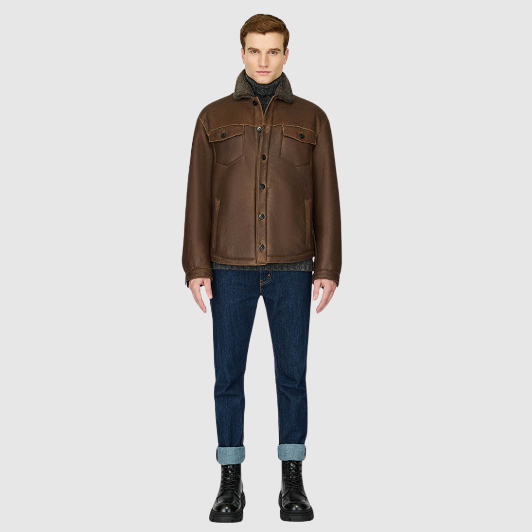 The PARRY Aged Bourbon Shearling Jacket delivers rugged refinement with a modern utilitarian edge. Crafted from semi-suede shearling, it features a semi-curly wool stand collar and a clean, semi-fitted silhouette through the shoulders, arms, and torso. Functional detailing includes chest patch pockets, sleeve button cuffs, and a mix of interior and exterior pockets for versatility. Finished with a single-breasted button closure, PARRY balances heritage shearling craftsmanship with contemporary shacket style