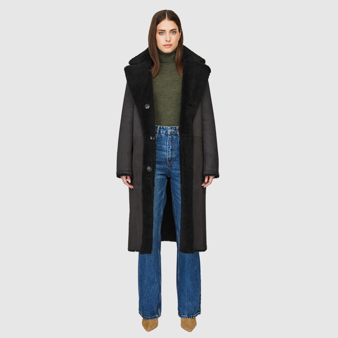 The HiSO Zira Grey Black Reversible Shearling features a vintage-inspired design, with a stylish suede curly wool on one side and cozy curly wool teddy on the other. It has a relaxed dropped shoulder and a three-button closure for a comfortable fit. The reversible nature of the jacket also includes a tie belt at the waist on the wool side and zip pockets on the suede side, while the teddy side has patch pockets.