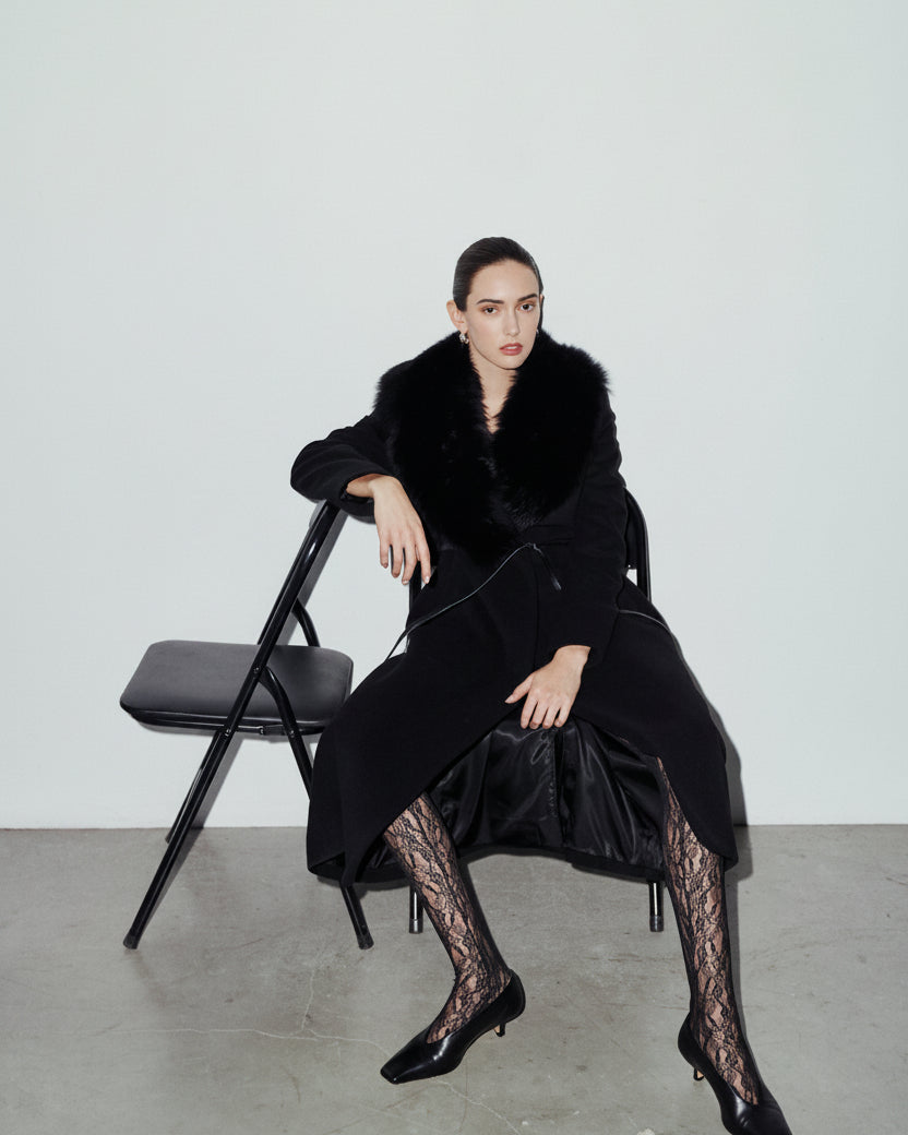 The ESTELLE Coat is a heritage-inspired full-length wool cashmere wrap coat crafted in deep jet black with a dramatic plush toscana wool shawl collar. Designed for a regular-fit fit with structured shoulders, a narrow leather tie belt, and a flared longline hem, ESTELLE combines modern edge with timeless texture. Functional welt side pockets and an open wrap front make this coat as practical as it is versatile, perfect for après-ski layering or elevated city styling.