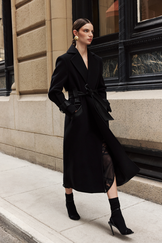 This sophisticated women's coat is a stylish wool trench coat featuring chic leather detail accents and distinctive sleeve straps. It boasts a classic notched collar. This elegant piece of outerwear offers a timeless silhouette. A perfect wool trench coat for a polished look.