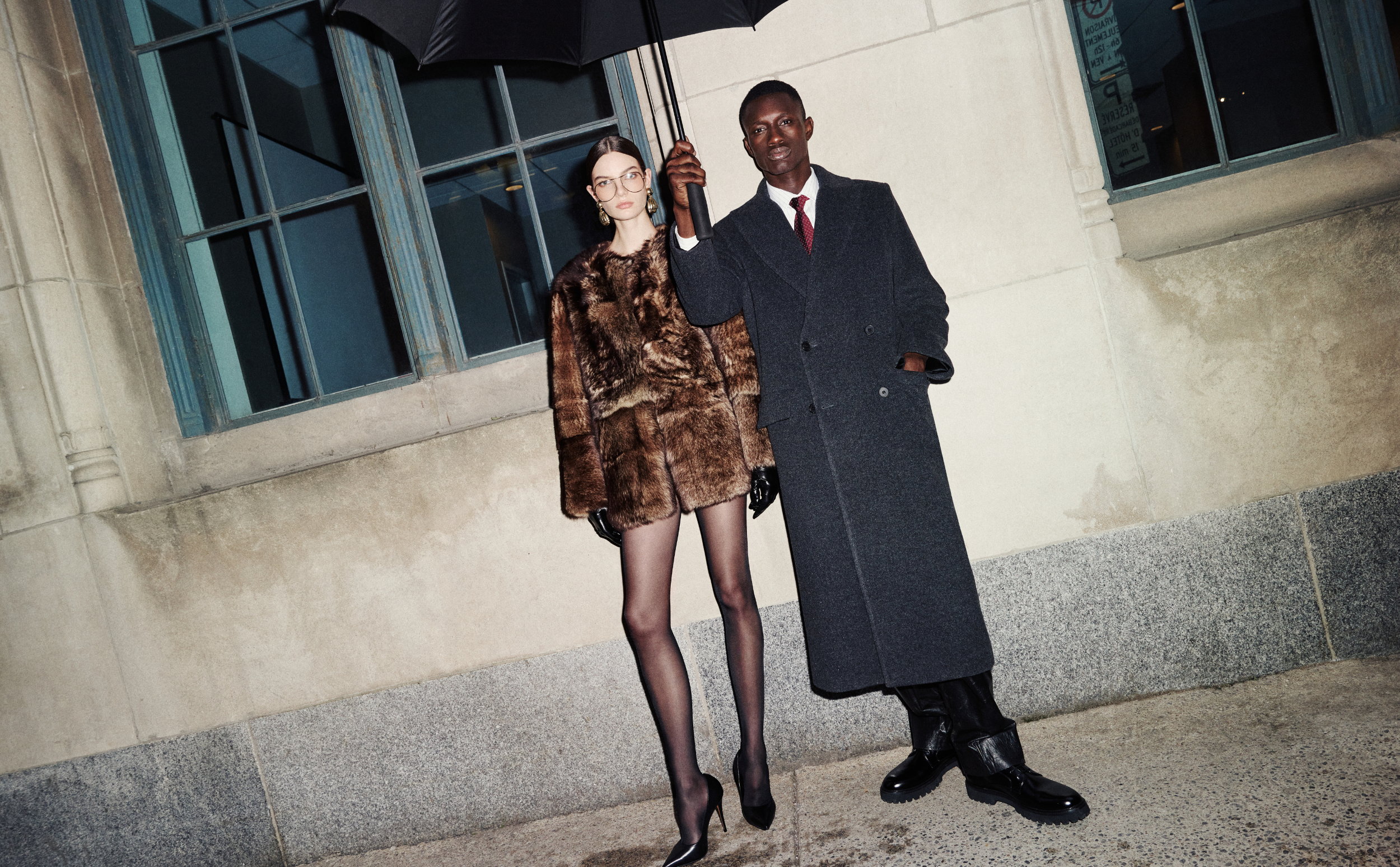 Two people standing under an umbrella in front of a building wearing HiSO. 