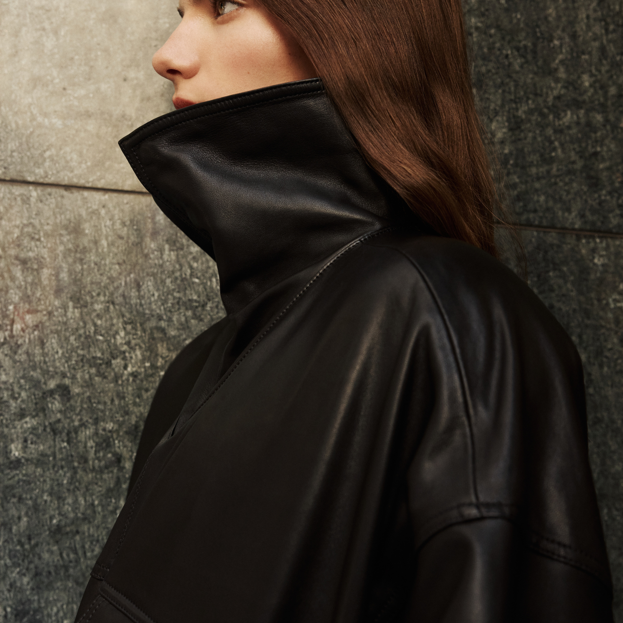 This stylish women's jacket is a chic piece of outerwear. Crafted from sleek leather, this coat features a modern, relaxed silhouette and a stand collar that can be worn up or folded down. It includes practical details such as front flap pockets and a gathered hem. This versatile leather jacket with its adaptable collar is perfect for adding an edgy yet sophisticated touch to any outfit. A must-have jacket for fashion-forward individuals seeking a contemporary coat option.