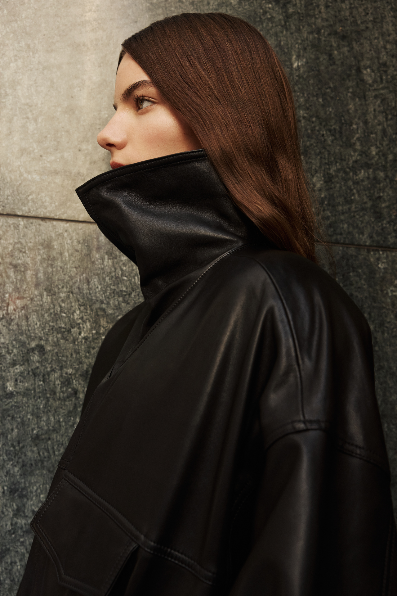 This stylish women's jacket is a chic piece of outerwear. Crafted from sleek leather, this coat features a modern, relaxed silhouette and a stand collar that can be worn up or folded down. It includes practical details such as front flap pockets and a gathered hem. This versatile leather jacket with its adaptable collar is perfect for adding an edgy yet sophisticated touch to any outfit. A must-have jacket for fashion-forward individuals seeking a contemporary coat option.