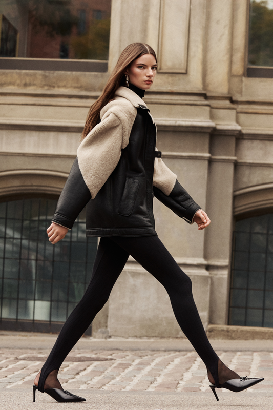 This stylish women's jacket is a versatile piece of outerwear: a chic nappa shearling design with cozy wool out details. This fashionable coat features a modern silhouette, a practical zip closure, and a convenient flap pocket. With removable sleeves, this clever jacket converts to a vest, offering multiple styling options. The luxurious shearling provides exceptional warmth and style. This adaptable outerwear piece is a must-have.