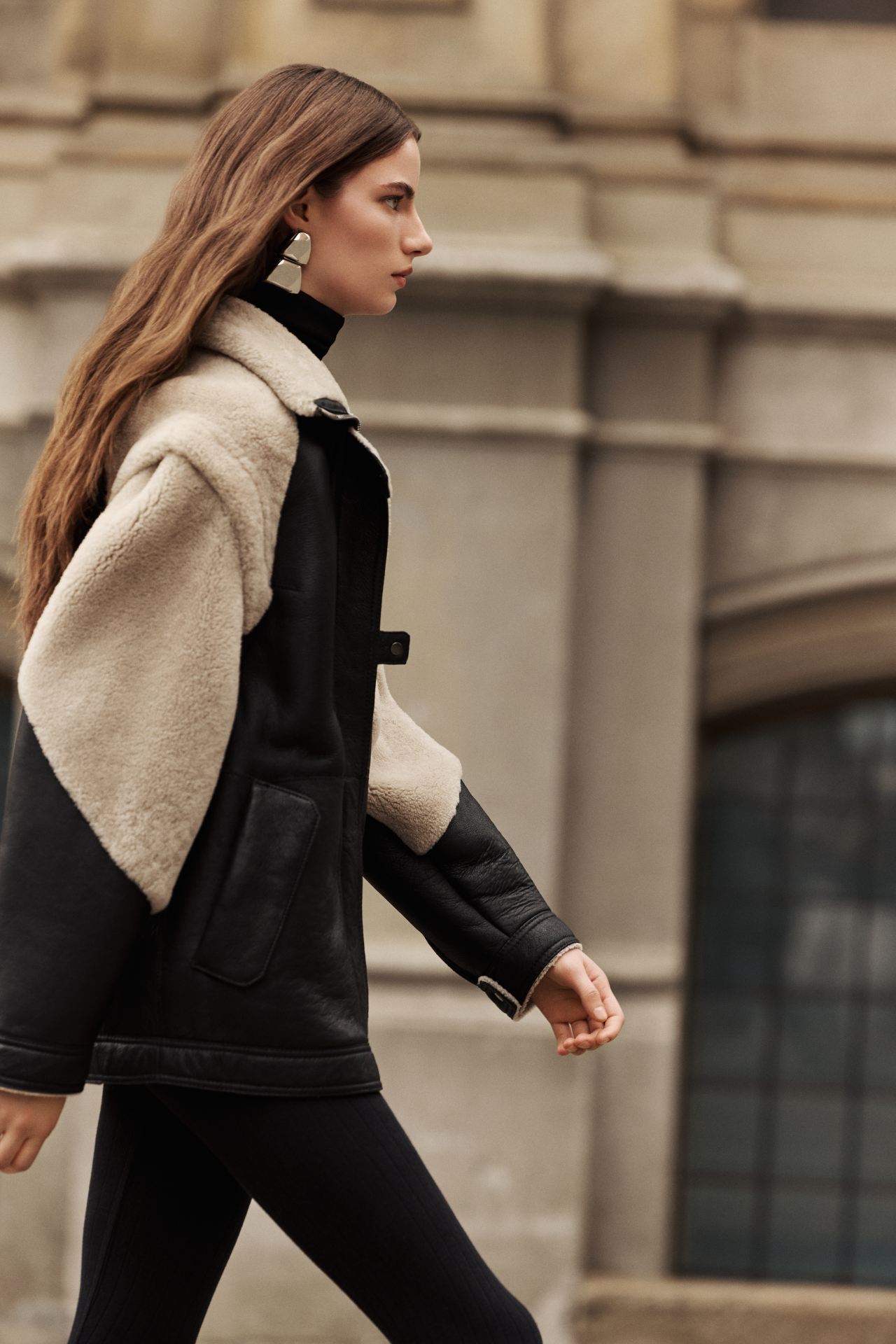 This stylish women's jacket is a versatile piece of outerwear: a chic nappa shearling design with cozy wool out details. This fashionable coat features a modern silhouette, a practical zip closure, and a convenient flap pocket. With removable sleeves, this clever jacket converts to a vest, offering multiple styling options. The luxurious shearling provides exceptional warmth and style. This adaptable outerwear piece is a must-have.