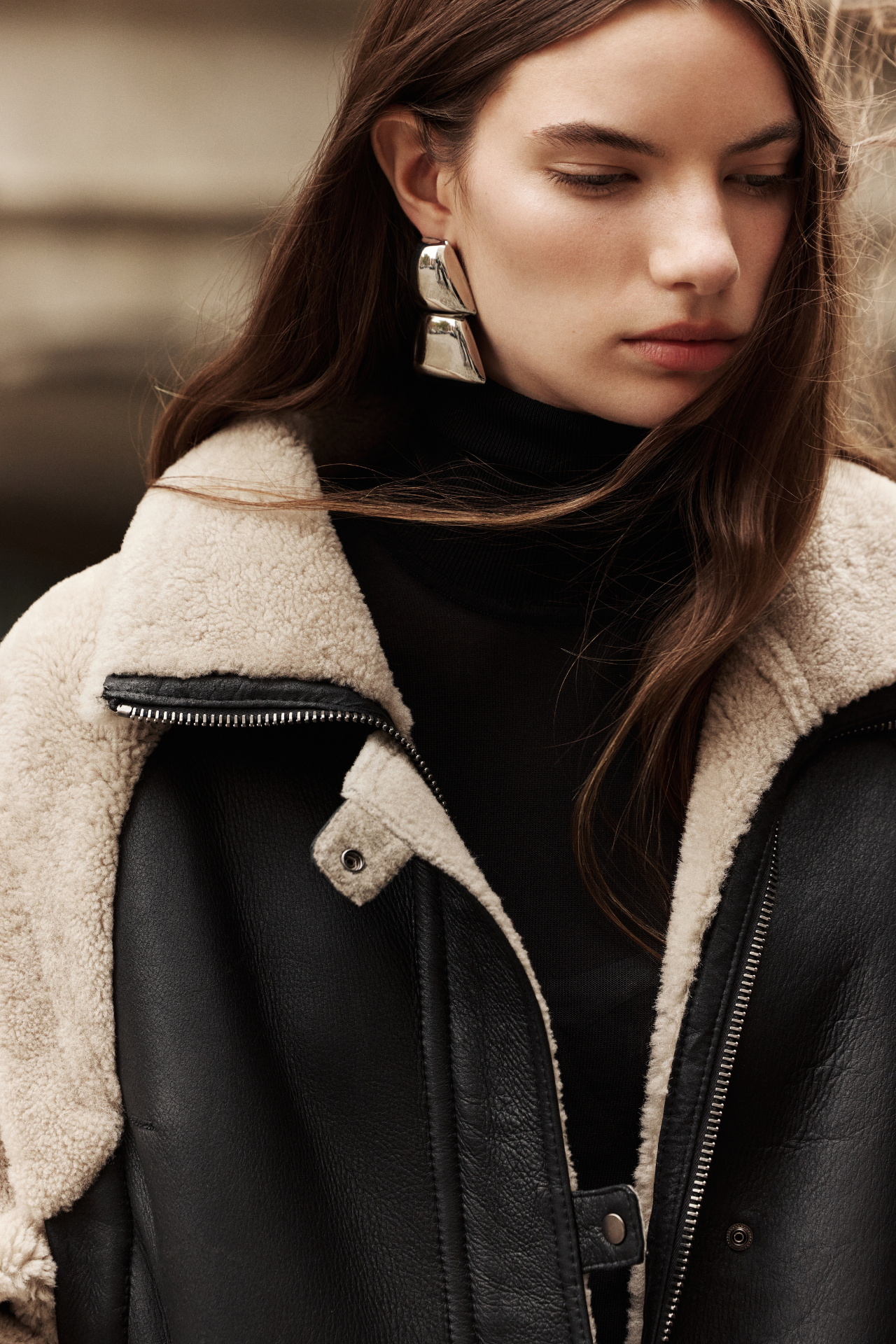 This stylish women's jacket is a versatile piece of outerwear: a chic nappa shearling design with cozy wool out details. This fashionable coat features a modern silhouette, a practical zip closure, and a convenient flap pocket. With removable sleeves, this clever jacket converts to a vest, offering multiple styling options. The luxurious shearling provides exceptional warmth and style. This adaptable outerwear piece is a must-have.