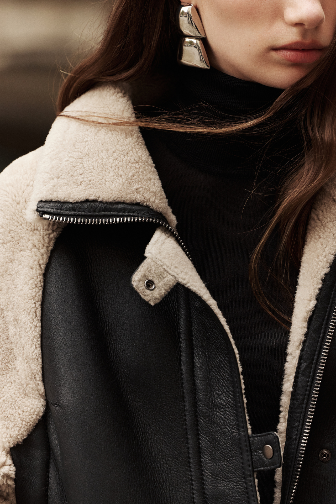 This stylish women's jacket is a versatile piece of outerwear: a chic nappa shearling design with cozy wool out details. This fashionable coat features a modern silhouette, a practical zip closure, and a convenient flap pocket. With removable sleeves, this clever jacket converts to a vest, offering multiple styling options. The luxurious shearling provides exceptional warmth and style. This adaptable outerwear piece is a must-have.