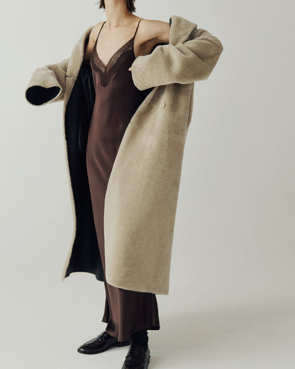 The DANIELLE Duster is a statement in heritage-inspired luxury and modern versatility. Crafted in black beige nappa and plush iron wool shearling, this reversible oversized coat transitions effortlessly from sleek leather to cozy teddy texture. Its elongated silhouette is enhanced with a slight drop shoulder, back vent, and double-breasted button closure, creating timeless elegance with functional edge. Practical single welt pockets on the suede side and slash pockets on the wool side