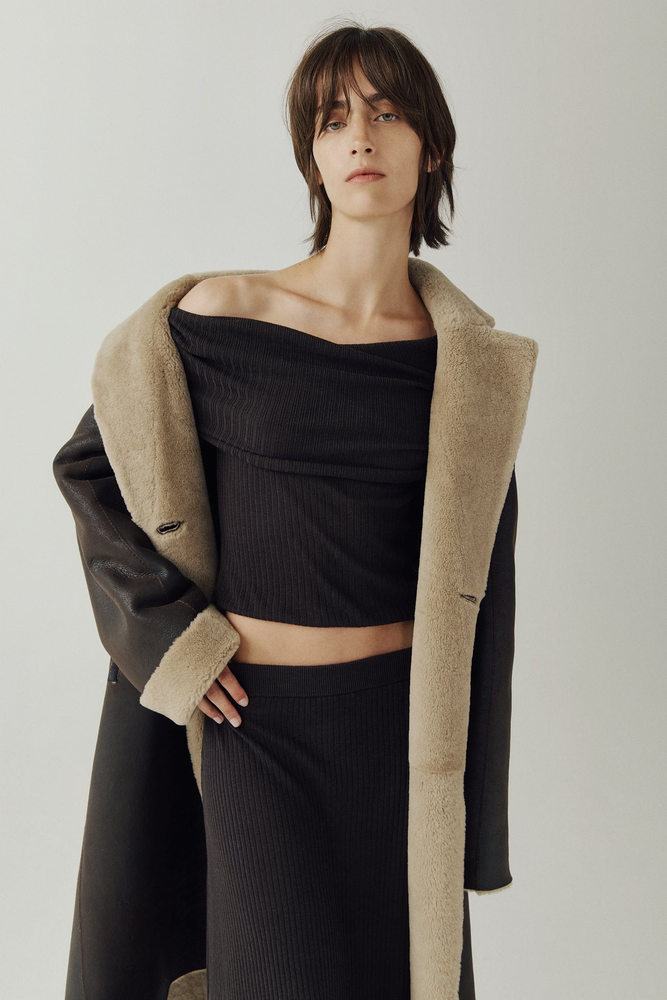 The ELLE Coat is a heritage-inspired oversized reversible shearling piece crafted in a oxen brown nappa ironed wool teddy. Designed to transition seamlessly from smooth suede to plush wool-out texture, this versatile style blends timeless tailoring with modern après-ski elegance. A slight drop shoulder, double-breasted button closure, and back vent add structure to its oversized silhouette. Functional single welt pockets on the suede side and slash pockets on the ironed wool side.