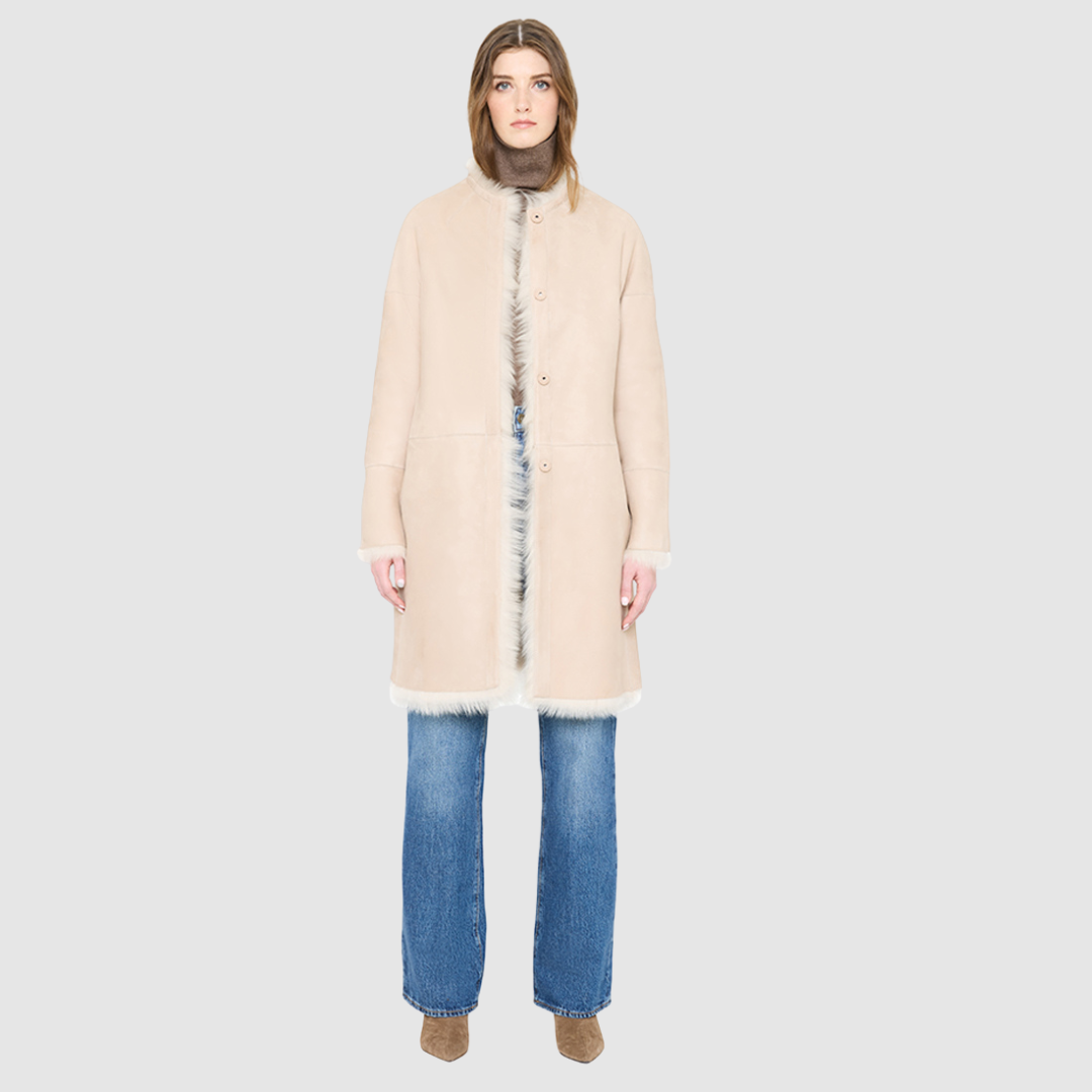 The ALLORA Jacket is a luxury reversible shearling teddy crafted in parchment toscana for a rich and modern finish. Designed as a collarless regular fitting silhouette, it effortlessly flips from plush wool-out shearling to a sleek suede skin-out jacket, offering two looks in one. With its generous fit through the shoulders, arms, and torso, ALLORA balances comfort and style. Functional slash side pockets on both sides and a front snap closure complete this elevated women’s reversible shearling jacket.