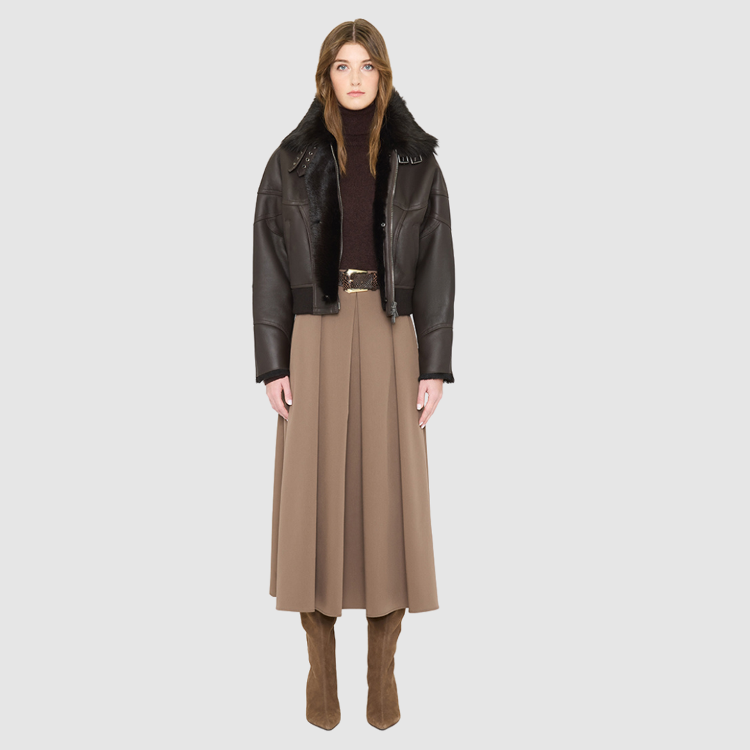 The CLARITY shearling bomber jacket offers a modern take on the classic bomber jacket, combining rugged function with luxurious texture. Crafted in a rich chocolate brown nappa leather and plush, dark rasado shearling wool interior, it delivers an elevated cold-weather look. Designed with a drop shoulder and a high shearling collar, it balances structure with relaxed ease. A tonal ribbed knit waistband, structural paneling, and clean hardware details lend utility to this elegant semi-fitted style