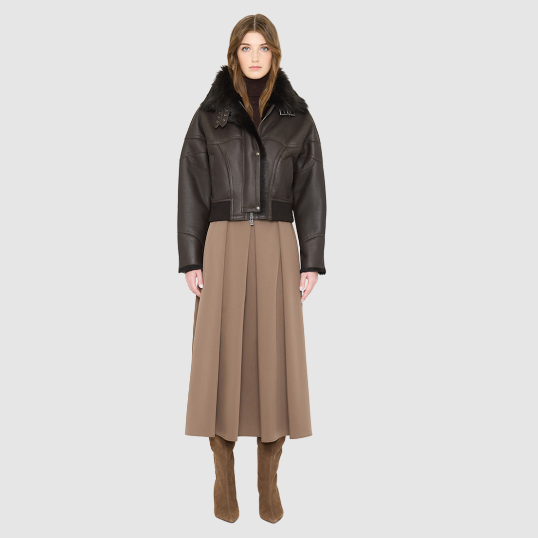 The CLARITY shearling bomber jacket offers a modern take on the classic bomber jacket, combining rugged function with luxurious texture. Crafted in a rich chocolate brown nappa leather and plush, dark rasado shearling wool interior, it delivers an elevated cold-weather look. Designed with a drop shoulder and a high shearling collar, it balances structure with relaxed ease. A tonal ribbed knit waistband, structural paneling, and clean hardware details lend utility to this elegant semi-fitted style