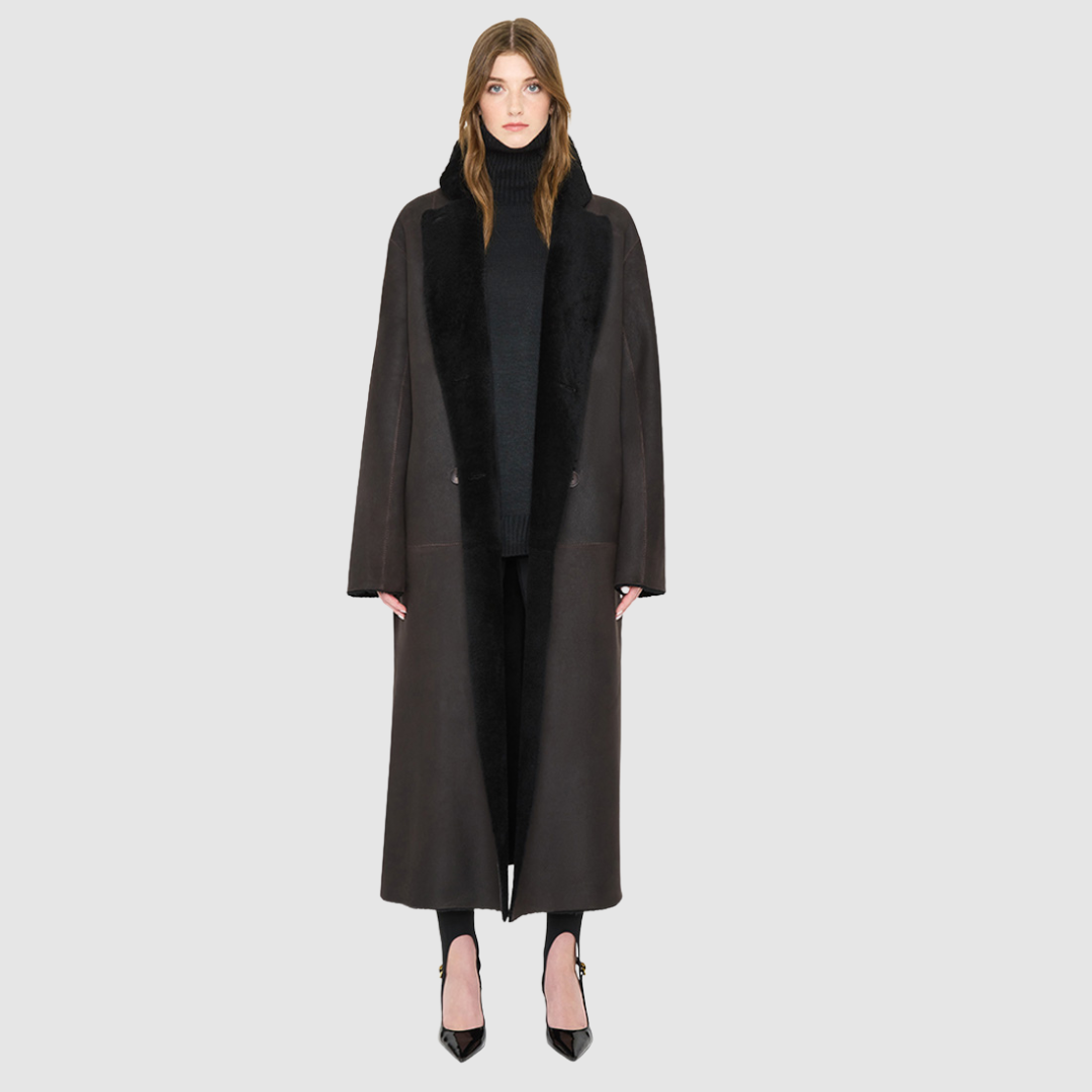 The DANIELLE Duster is a statement in heritage-inspired luxury and modern versatility. Crafted in java semi suede leather and plush curly wool shearling, this reversible oversized coat transitions effortlessly from sleek leather to cozy teddy texture. Its elongated silhouette is enhanced with a slight drop shoulder, back vent, and double-breasted button closure, creating timeless elegance with functional edge. Practical single welt pockets on the semi suede side and slash pockets on the wool side