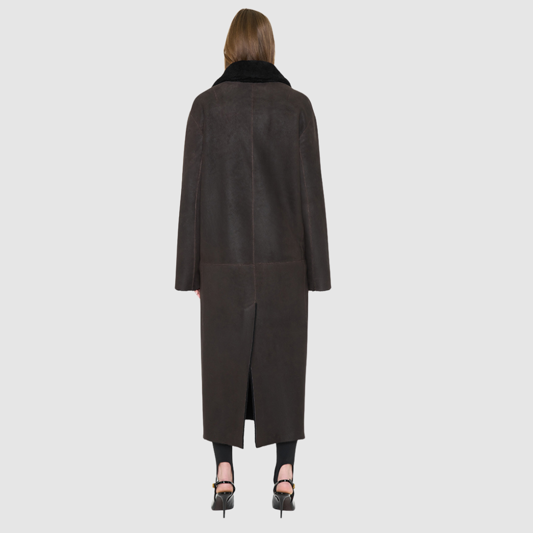 The DANIELLE Duster is a statement in heritage-inspired luxury and modern versatility. Crafted in java semi suede leather and plush curly wool shearling, this reversible oversized coat transitions effortlessly from sleek leather to cozy teddy texture. Its elongated silhouette is enhanced with a slight drop shoulder, back vent, and double-breasted button closure, creating timeless elegance with functional edge. Practical single welt pockets on the semi suede side and slash pockets on the wool side