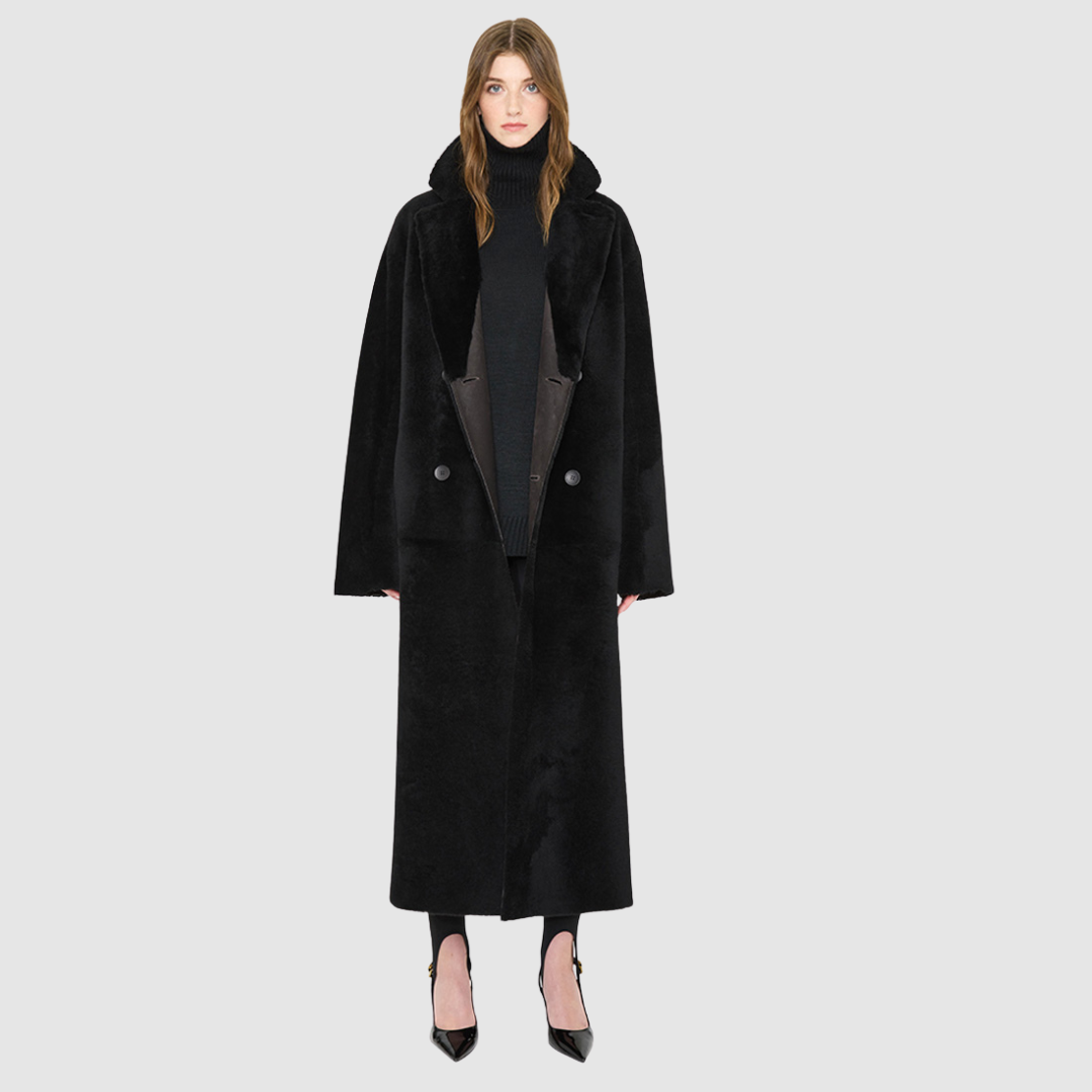 The DANIELLE Duster is a statement in heritage-inspired luxury and modern versatility. Crafted in java semi suede leather and plush curly wool shearling, this reversible oversized coat transitions effortlessly from sleek leather to cozy teddy texture. Its elongated silhouette is enhanced with a slight drop shoulder, back vent, and double-breasted button closure, creating timeless elegance with functional edge. Practical single welt pockets on the semi suede side and slash pockets on the wool side