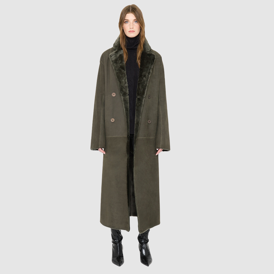 The DANIELLE Duster is a statement in heritage-inspired luxury and modern versatility. Crafted in khaki suede leather and plush curly wool shearling, this reversible oversized coat transitions effortlessly from sleek leather to cozy teddy texture. Its elongated silhouette is enhanced with a slight drop shoulder, back vent, and double-breasted button closure, creating timeless elegance with functional edge. Practical single welt pockets on the suede side and slash pockets on the wool side.