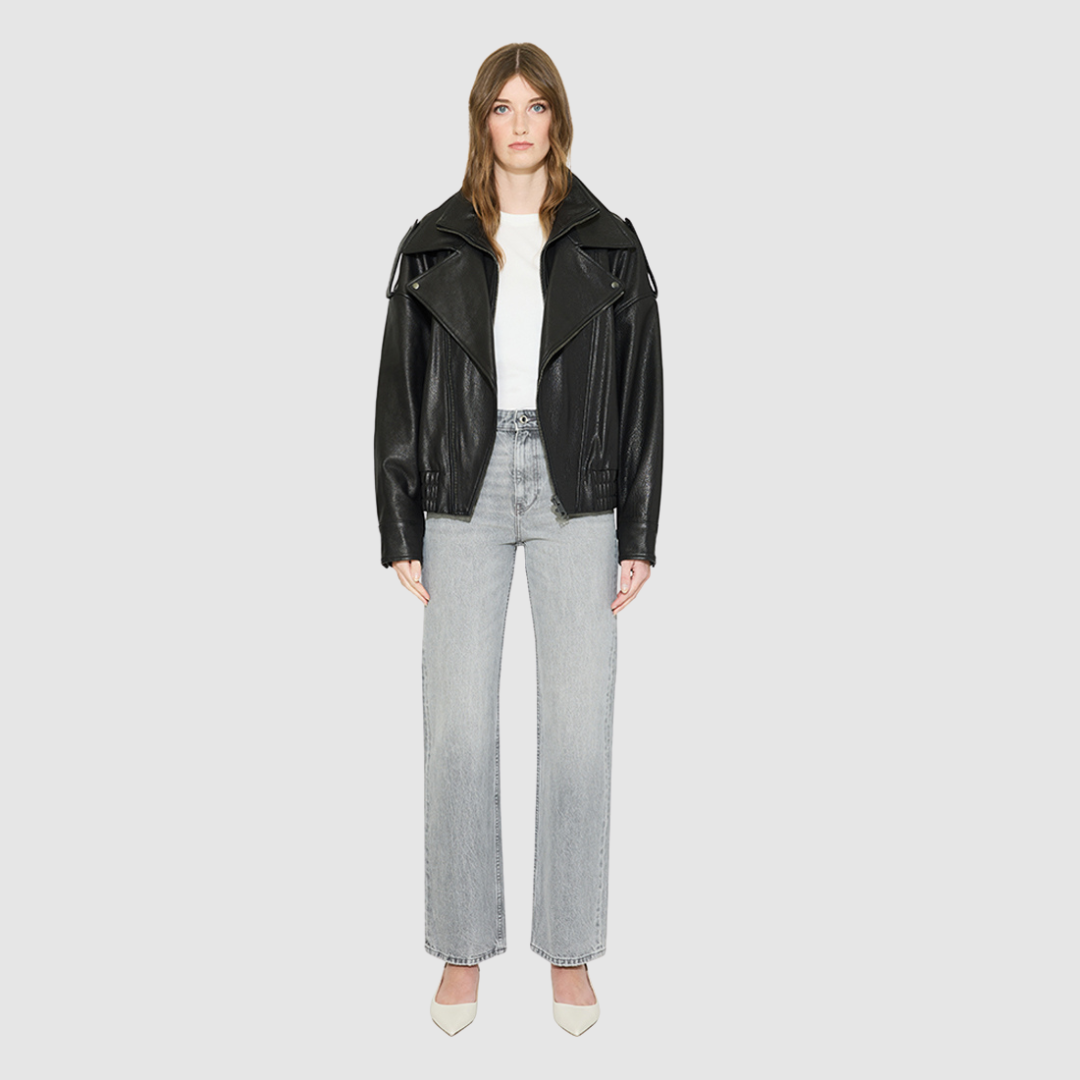 The HELENA Leather Jacket is a modern oversized biker-inspired silhouette crafted in premium textured black leather. Designed with drop shoulders, shoulder epaulet details, and relaxed volume through the body, it delivers sharp architectural lines with an effortless, edgy drape. An oversized notched biker collar and asymmetric front zip closure give it a clean, directional finish, while a gathered elasticized back hem defines the waist. Fully lined for comfort, HELENA serves as a definitive statement piece 