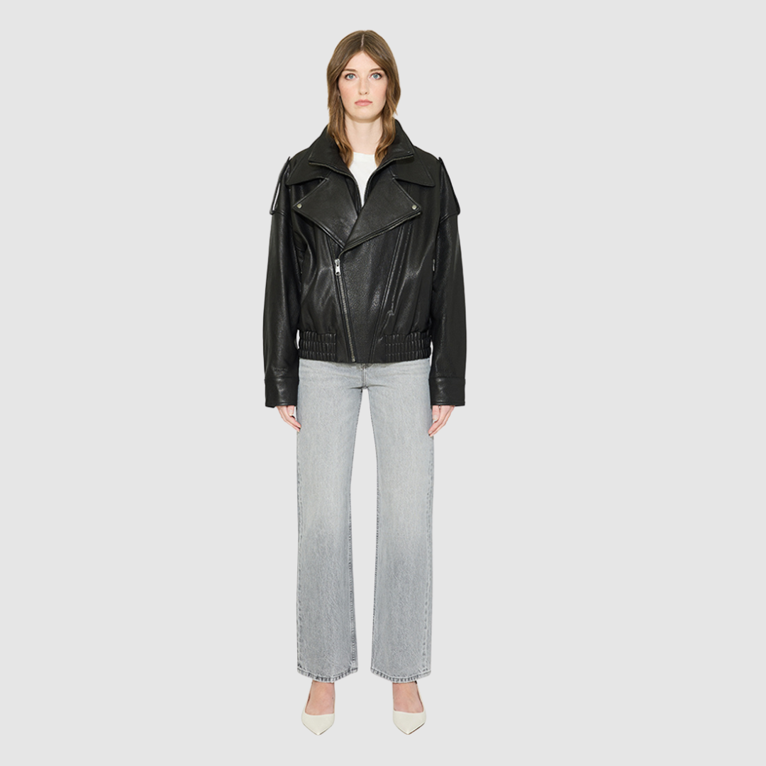 The HELENA Leather Jacket is a modern oversized biker-inspired silhouette crafted in premium textured black leather. Designed with drop shoulders, shoulder epaulet details, and relaxed volume through the body, it delivers sharp architectural lines with an effortless, edgy drape. An oversized notched biker collar and asymmetric front zip closure give it a clean, directional finish, while a gathered elasticized back hem defines the waist. Fully lined for comfort, HELENA serves as a definitive statement piece 
