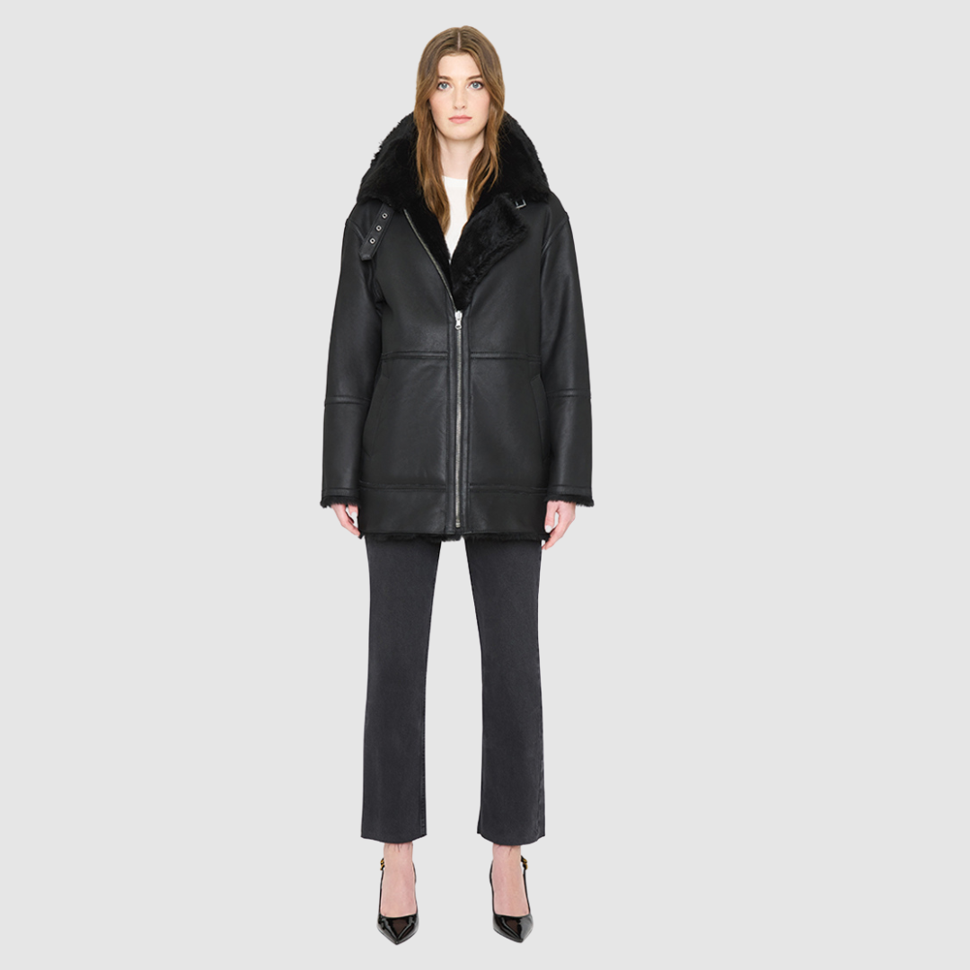 JILL is a heritage-inspired reversible medium-length shearling car coat crafted in jet black matte nappa leather with smooth ironed wool teddy on the reverse. Designed for a relaxed silhouette with regular shoulders, an exaggerated spread collar with adjustable leather strap detail, and a straight fit, JILL combines modern edge with timeless texture. Functional deep patch pockets on the wool side, clean welt pockets on the nappa side, and a heavy-duty front zip closure 