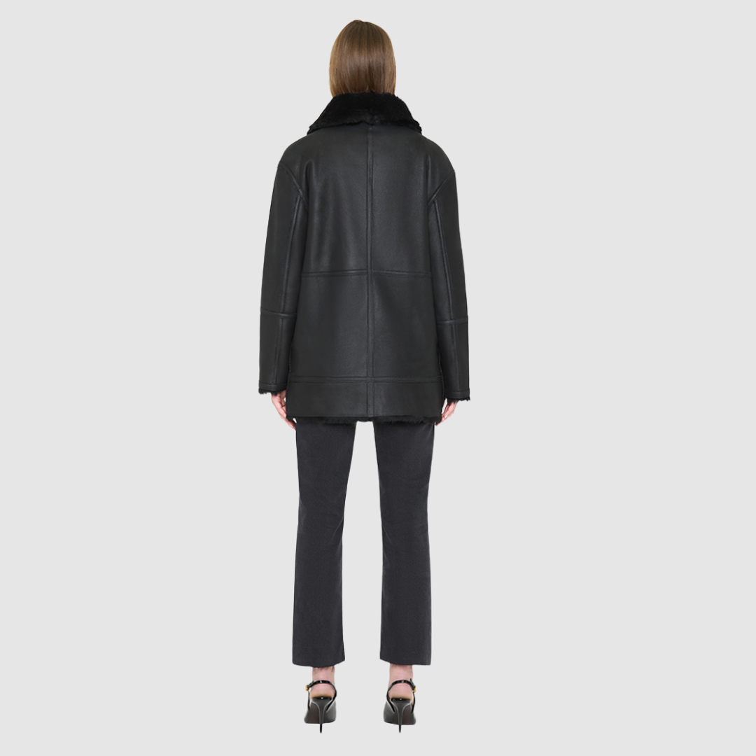 JILL is a heritage-inspired reversible medium-length shearling car coat crafted in jet black matte nappa leather with smooth ironed wool teddy on the reverse. Designed for a relaxed silhouette with regular shoulders, an exaggerated spread collar with adjustable leather strap detail, and a straight fit, JILL combines modern edge with timeless texture. Functional deep patch pockets on the wool side, clean welt pockets on the nappa side, and a heavy-duty front zip closure 