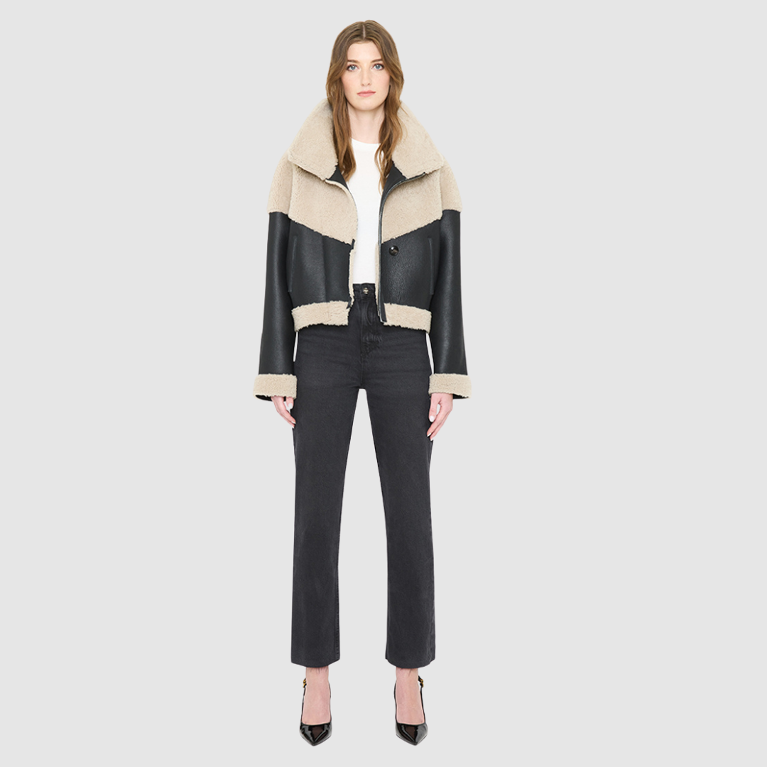 The LILITH Jacket is a heritage-inspired cropped shearling jacket crafted from black nappa leather with plush, contrasting beige wool detailing for modern texture and dimension. Its drop shoulder and relaxed cropped silhouette create a sleek, contemporary fit, while a dramatic chevron-blocked design across the chest, shoulders, and sleeves adds a striking graphic edge. Featuring a multi-functional front zip closure that deep side pockets, and exposed beige shearling trim at the cuffs and hem, LILITH is as p