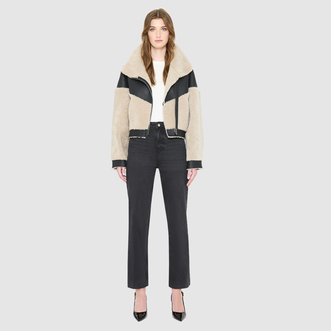 The LILITH Jacket is a heritage-inspired cropped shearling jacket crafted from black nappa leather with plush, contrasting beige wool detailing for modern texture and dimension. Its drop shoulder and relaxed cropped silhouette create a sleek, contemporary fit, while a dramatic chevron-blocked design across the chest, shoulders, and sleeves adds a striking graphic edge. Featuring a multi-functional front zip closure that deep side pockets, and exposed beige shearling trim at the cuffs and hem, LILITH is as p