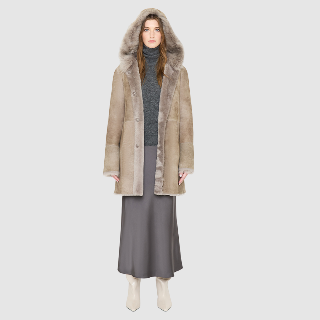 The LOVER reversible shearling jacket offers a modern take on the classic hooded long coat, combining rugged function with luxurious texture. Crafted in a rich smoked quartz suede that reverses to a plush, toscana rasado wool interior, it delivers two distinct looks in one. Designed with a regular shoulder and an oversized shearling hood, it balances structure with relaxed ease. Clean tailored panels and versatile integrated pocketing lend utility to this elegant semi-fitted style