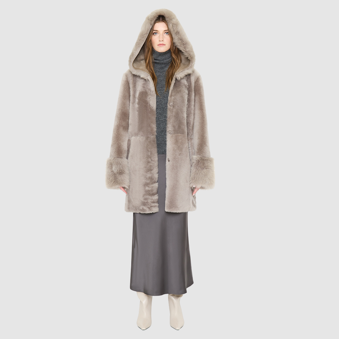 The LOVER reversible shearling jacket offers a modern take on the classic hooded long coat, combining rugged function with luxurious texture. Crafted in a rich smoked quartz suede that reverses to a plush, toscana rasado wool interior, it delivers two distinct looks in one. Designed with a regular shoulder and an oversized shearling hood, it balances structure with relaxed ease. Clean tailored panels and versatile integrated pocketing lend utility to this elegant semi-fitted style