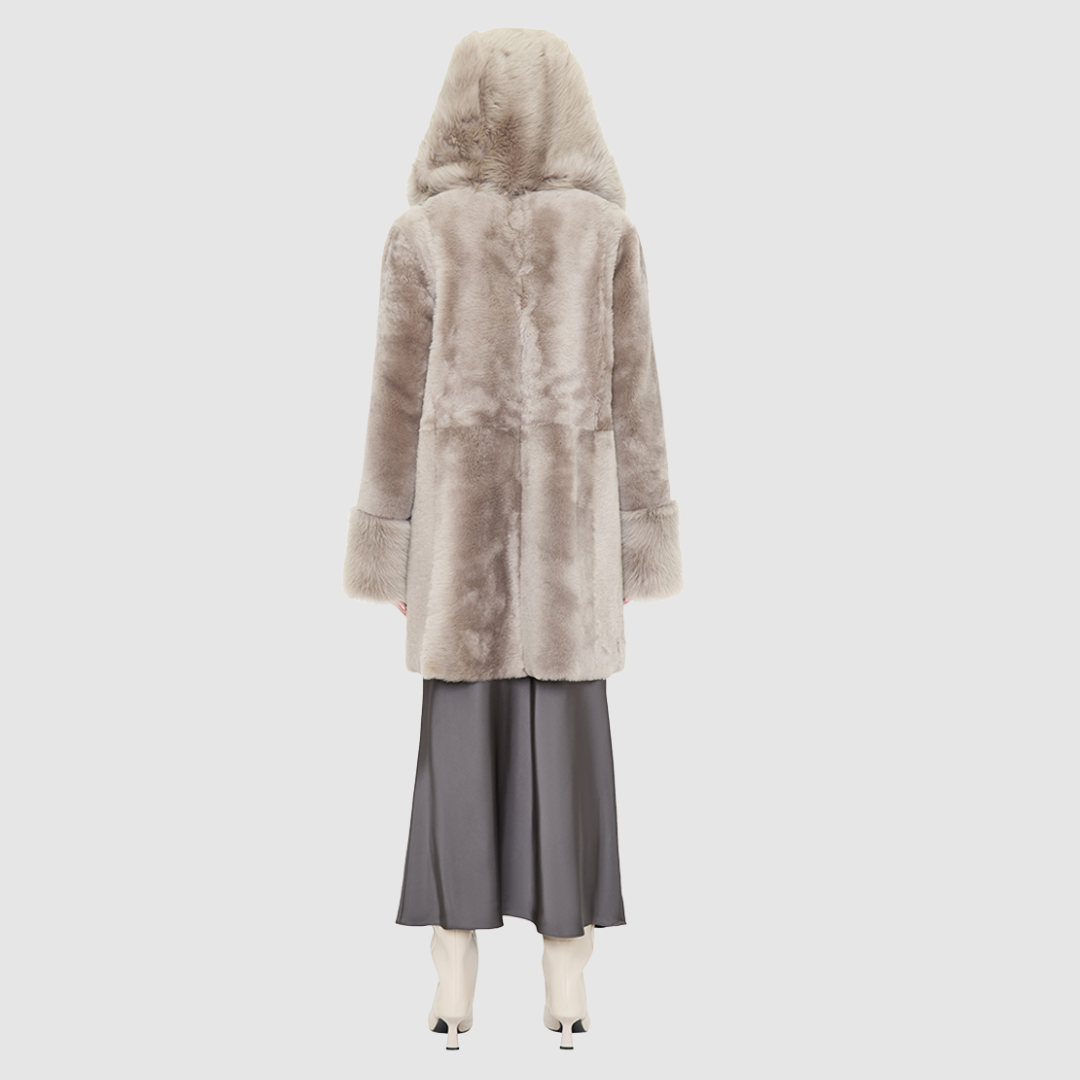 The LOVER reversible shearling jacket offers a modern take on the classic hooded long coat, combining rugged function with luxurious texture. Crafted in a rich smoked quartz suede that reverses to a plush, toscana rasado wool interior, it delivers two distinct looks in one. Designed with a regular shoulder and an oversized shearling hood, it balances structure with relaxed ease. Clean tailored panels and versatile integrated pocketing lend utility to this elegant semi-fitted style