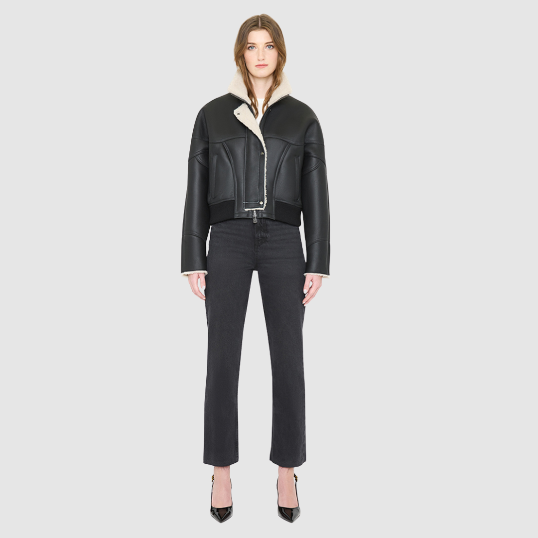 The LUMI Jacket is a heritage-inspired cropped shearling aviator crafted from black nappa leather and plush cream wool detailing for modern texture and dimension. Its regular shoulder and tailored cropped silhouette create a sleek, contemporary fit, while architectural paneled lines add a clean, minimalist edge. Functional exterior welt pockets, front zip closure, and a thick tonal ribbed knit waistband make LUMI as practical as it is stylish, perfect for après-ski layering or urban winter looks.