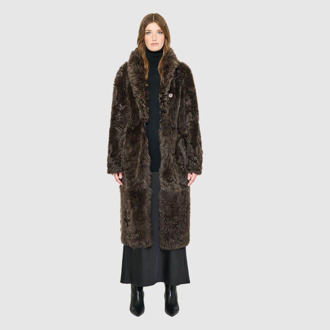OMEGA introduces an element of understated luxury to cold-weather dressing, offering a longline silhouette engineered for seasonal transition. This exquisite investment outerwear piece pairs a deep carbon suede exterior skin with a rich, magnificent semi curly toscana wool teddy on the reverse side. Designed to shift seamlessly from a dramatic, texture-forward profile to a classic, minimalist skin-out aesthetic, this fully reversible coat adapts effortlessly to your outfit. 
