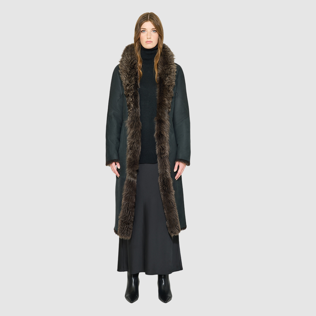 OMEGA introduces an element of understated luxury to cold-weather dressing, offering a longline silhouette engineered for seasonal transition. This exquisite investment outerwear piece pairs a deep carbon suede exterior skin with a rich, magnificent semi curly toscana wool teddy on the reverse side. Designed to shift seamlessly from a dramatic, texture-forward profile to a classic, minimalist skin-out aesthetic, this fully reversible coat adapts effortlessly to your outfit. 