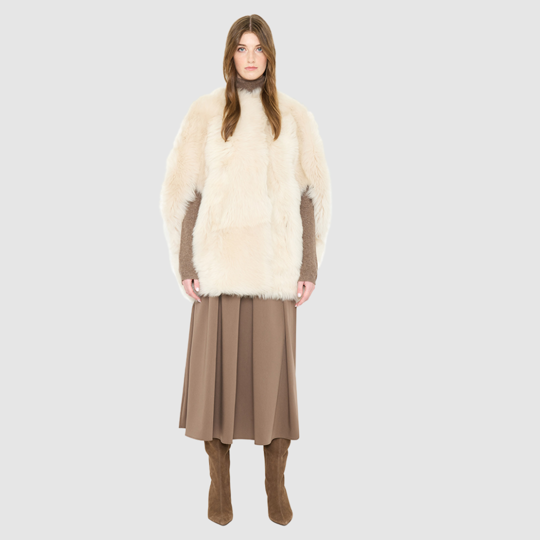 The ROTHEN Cocoon Vest is a modern oversized silhouette crafted in luxurious parchment-toned toscana wool. Designed with a generous drop shoulder and a relaxed, fluid drape, it delivers effortless volume and architectural style. A collarless neckline and discrete button closure give it a clean, minimalist finish, while a fully reversible design shifts from a suede side to a plush toscana teddy side for versatile styling. Providing ultimate natural insulation, ROTHEN is the ultimate statement piece for eleva