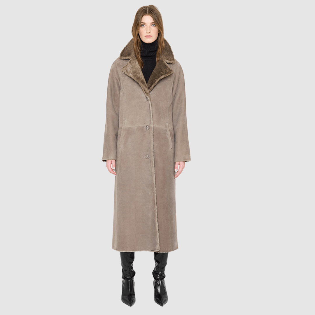 The SAVVY Coat is a modern full-length silhouette crafted in premium taupe badger shearling. Designed with regular shoulders and an easy, relaxed drape, it delivers sophisticated volume and architectural presence. A substantial notch collar and single-breasted button closure give it a clean, minimalist finish, while a fully reversible construction shifts from a refined suede side to a plush, iron wool side for versatile styling. Providing ultimate natural warmth, SAVVY serves as a definitive statement coat 