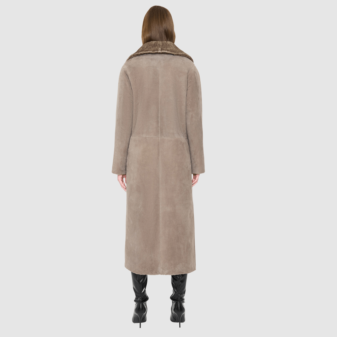 The SAVVY Coat is a modern full-length silhouette crafted in premium taupe badger shearling. Designed with regular shoulders and an easy, relaxed drape, it delivers sophisticated volume and architectural presence. A substantial notch collar and single-breasted button closure give it a clean, minimalist finish, while a fully reversible construction shifts from a refined suede side to a plush, iron wool side for versatile styling. Providing ultimate natural warmth, SAVVY serves as a definitive statement coat 