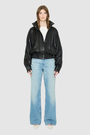 The WREN Bomber Jacket is a modern silhouette crafted in supple black nappa leather. Designed with raglan drop shoulders and an easy, relaxed volume through the body, it delivers sharp architectural presence with a sporty edge. A high stand funnel collar and concealed front zip closure with snap storm placket give it a clean, minimalist finish, while a gathered elasticized leather hem defines the waist. Fully lined for comfort, WREN serves as a definitive statement piece for transitional and cold-weather