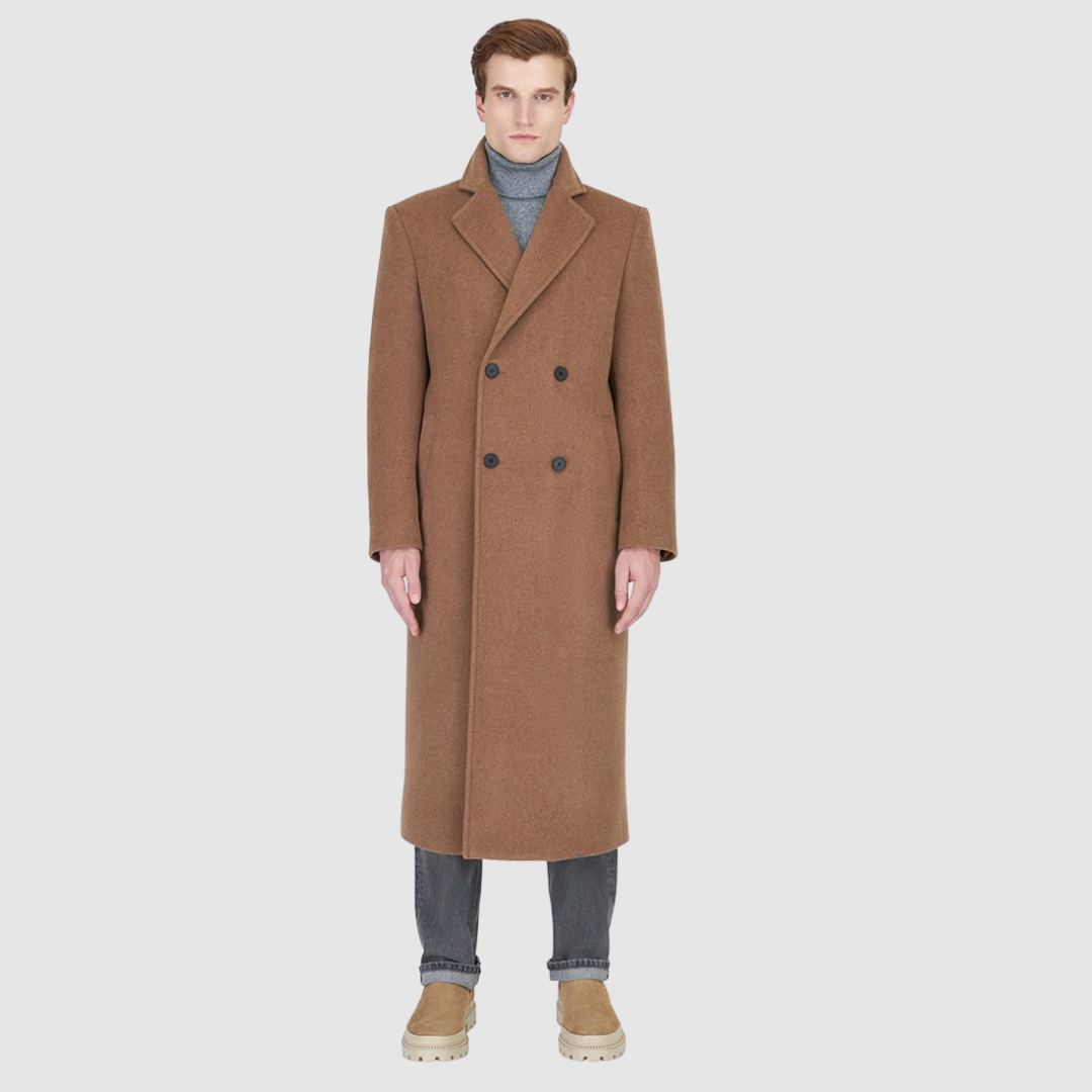 The ATLAS Coat is an elongated double-breasted silhouette crafted from a premium wool blend in an camel melange hue. Designed with structured shoulders and a tailored regular fit through the body, it delivers sharp architectural lines and a refined drape. A wide notch lapel and double-breasted button closure give it a clean, minimalist finish, while discrete side welt pockets and a single back vent add classic functionality. Fully lined for comfort, ATLAS serves as a  statement piece for cold-weather